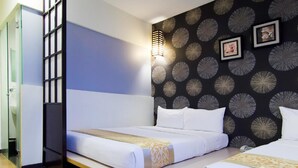Ein Hotelzimmer mit Bett, Nachttisch, Wand mit kreisförmigem Muster und Fenster mit Blick nach draußen.