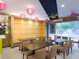 Interior de restaurante com cabines, mesas e lanternas cor-de-rosa.