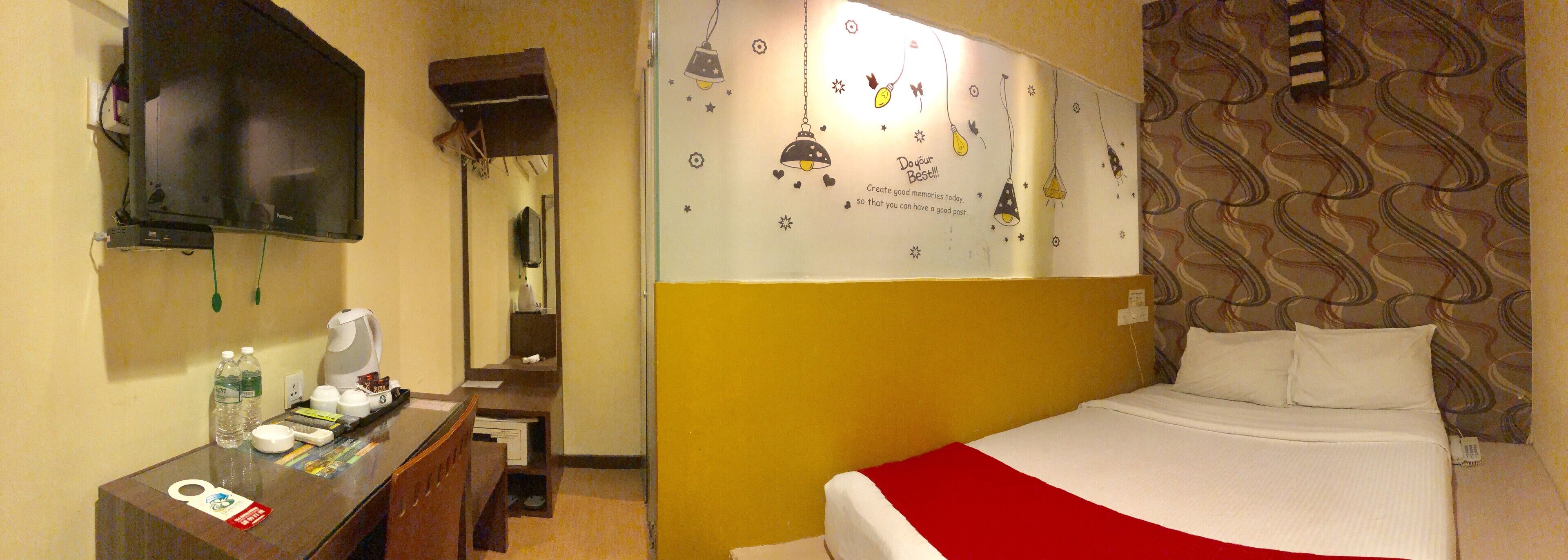 A hotel room with a bed, a desk with a telephone, a television, and a mirror.