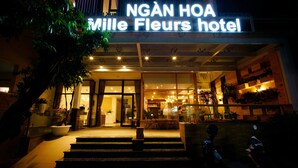 Exterior del hotel NGÂN HOA Miele Fleurs, con una entrada bien iluminada, escalones que conducen a la puerta y plantas en macetas alrededor.