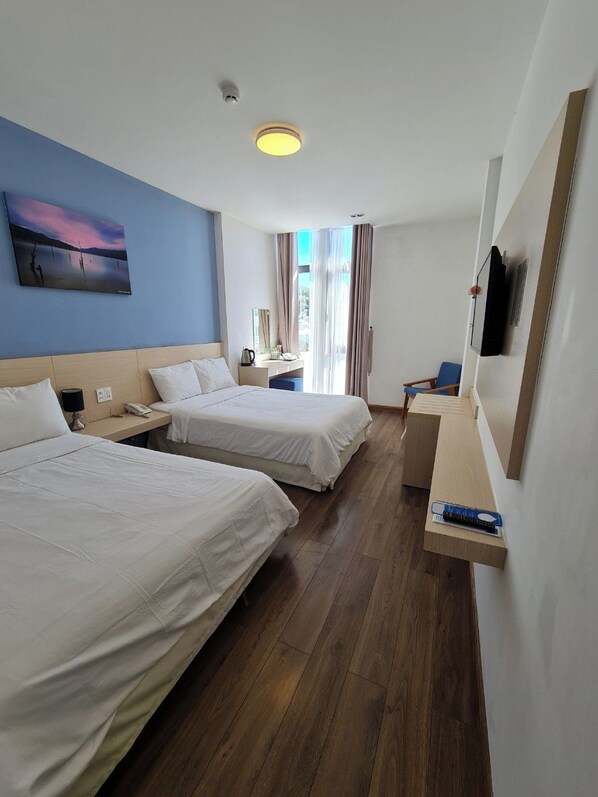 A hotel room with two beds, a desk, a chair, a TV, and a painting on the wall.