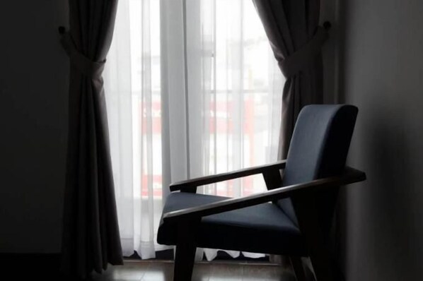 A chair in a room with a large window and sheer curtains. - Mille Fleurs Hotel (Xuan Huong - Da Lat)