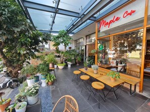 An outdoor seating area with potted plants and a Maple Cafe sign. - Mille Fleurs Hotel (Xuan Huong - Da Lat)