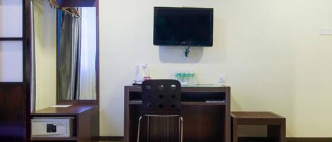 A hotel room with two beds, a desk with a chair, a television, an air conditioning unit, and a mirror.