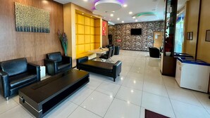 A modern hotel lobby with leather sofas, a coffee table, a reception desk, and a decorative wall. - Eight Days Boutique Hotel (Johor Bahru)