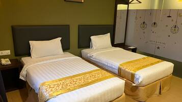 A hotel room with two beds, a bedside table with a phone, a wall-mounted lamp, and a decorative wall with hanging lights.