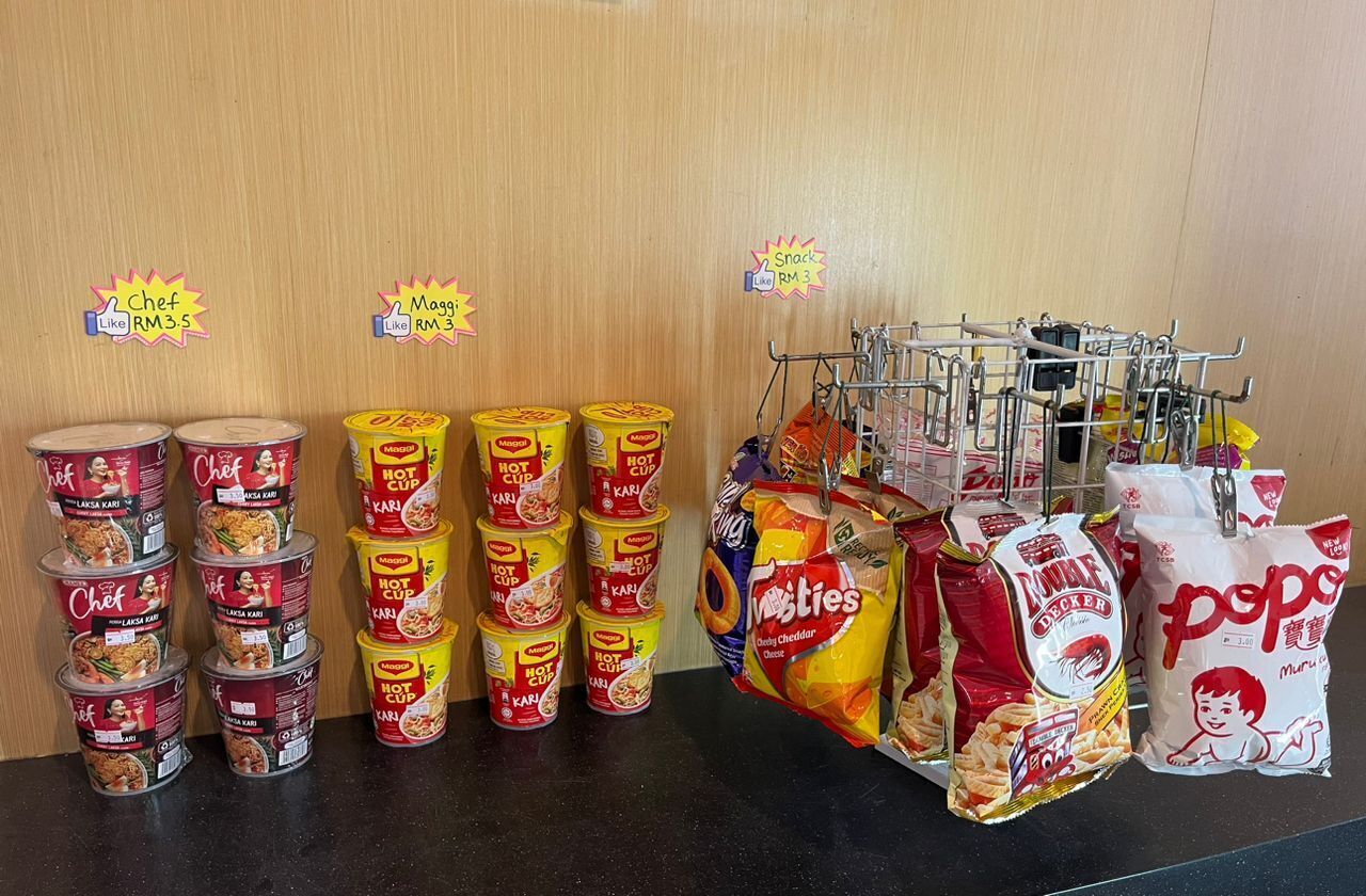 A snack display with various items like Chef's Laksa, Maggi Hot Cup, Mie's, and other snacks.