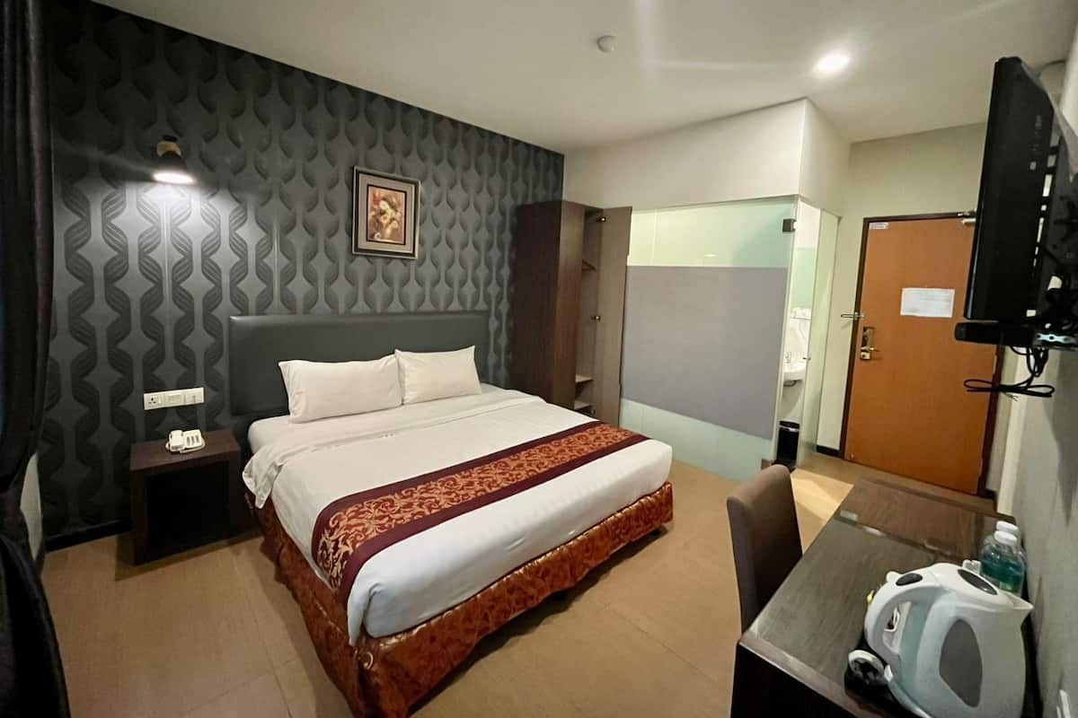 Une chambre d’hôtel comprenant un lit, une table de chevet, une télévision et un bureau avec une chaise.