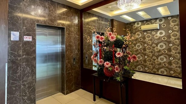 A modern elevator, a floral arrangement, and a patterned wall in a lobby area. - Eight Days Boutique Hotel (Johor Bahru)