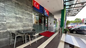 A modern hotel entrance with a glass facade, a red carpet, and two flags. - Eight Days Boutique Hotel (Johor Bahru)