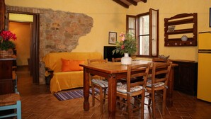 A cozy living area with a stone wall, wooden furniture, and a tiled floor. - Casale Vigna Carbona (Gavorrano)