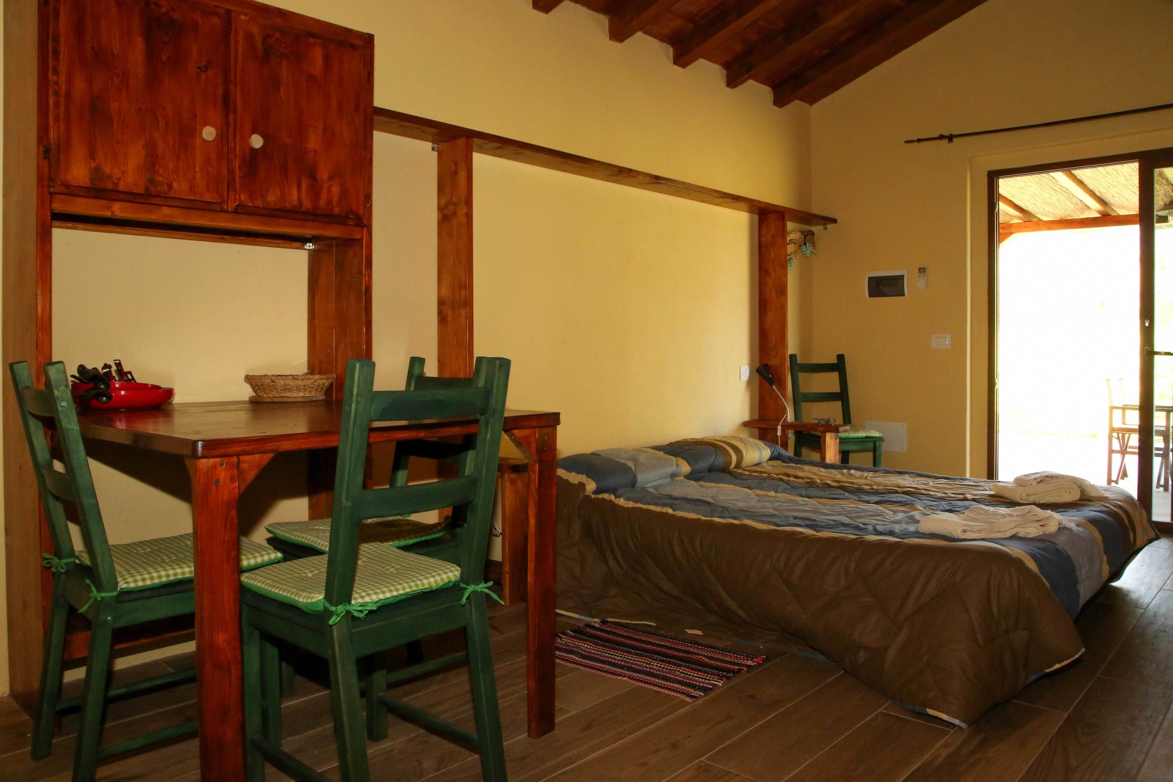 A bedroom with a bed, a wooden table, and two chairs.