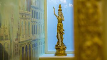 A golden statue on a pedestal in a room with a window.
