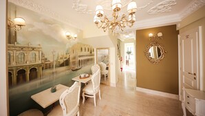 Un comedor con un mural de un paisaje urbano, candelabros ornamentales y un juego de mesa blanco.