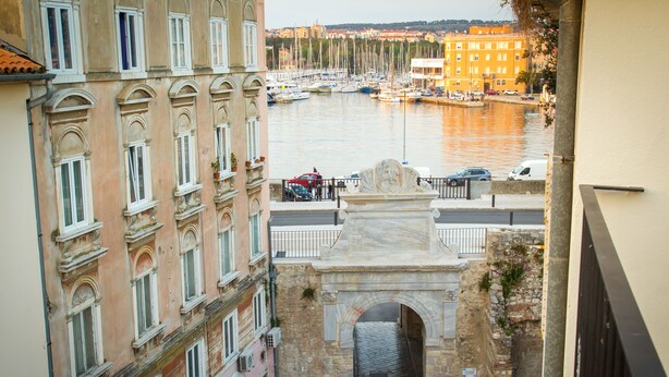 Vista de una ciudad histórica con un canal, edificios de piedra y una estatua.