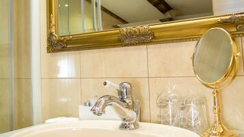 A bathroom with a marble sink, a gold-framed mirror, and a small round mirror.