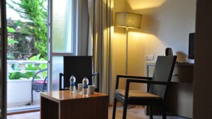 A modern hotel room with a wooden desk, two chairs, a lamp, and a view of greenery outside. - Dragos Island Hotel (Istanbul)