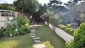A garden with a stone pathway, lush greenery, and a white fence. - Dragos Island Hotel (Istanbul)