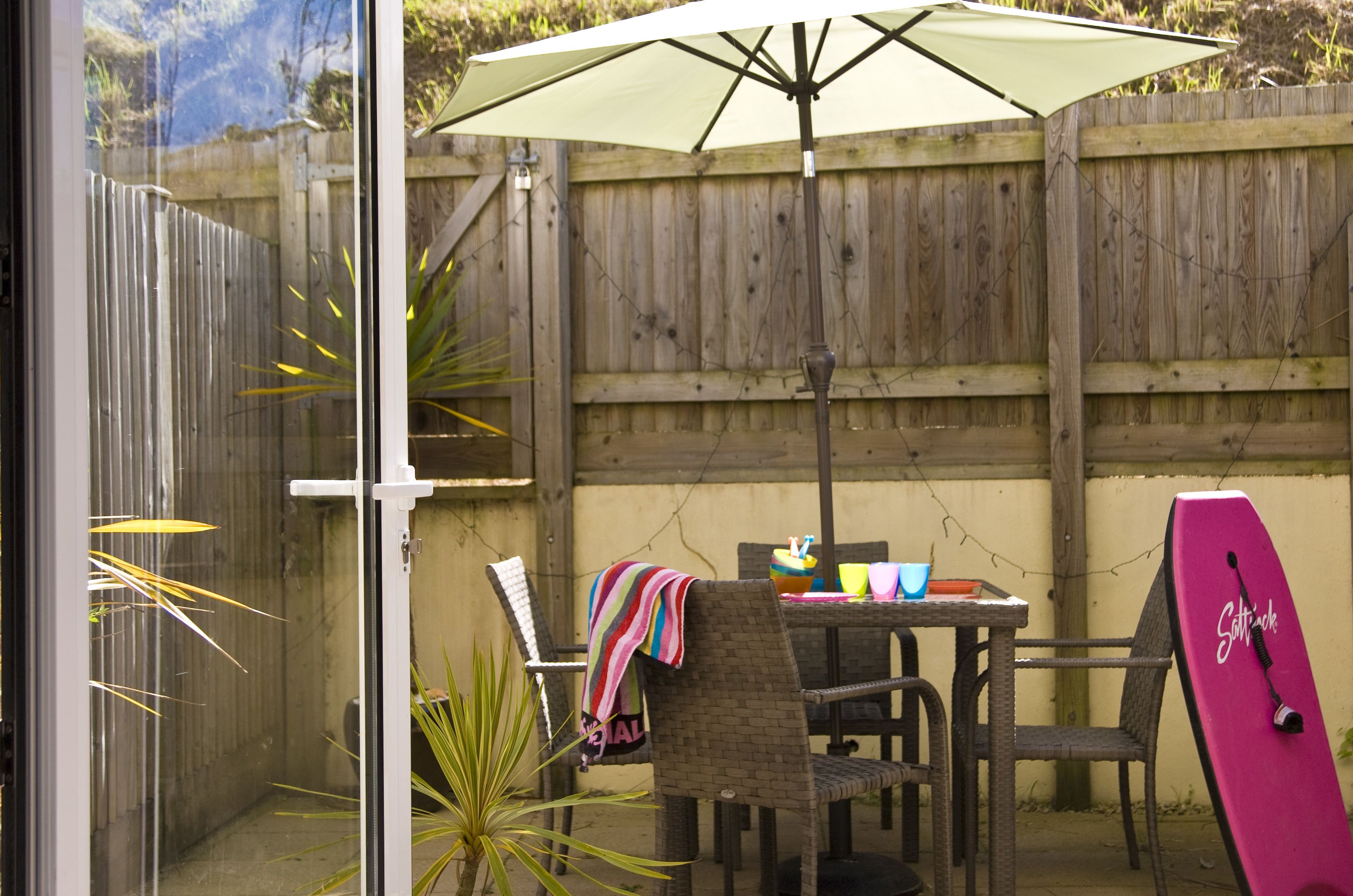 Une terrasse avec une table, des chaises et une planche de surf.