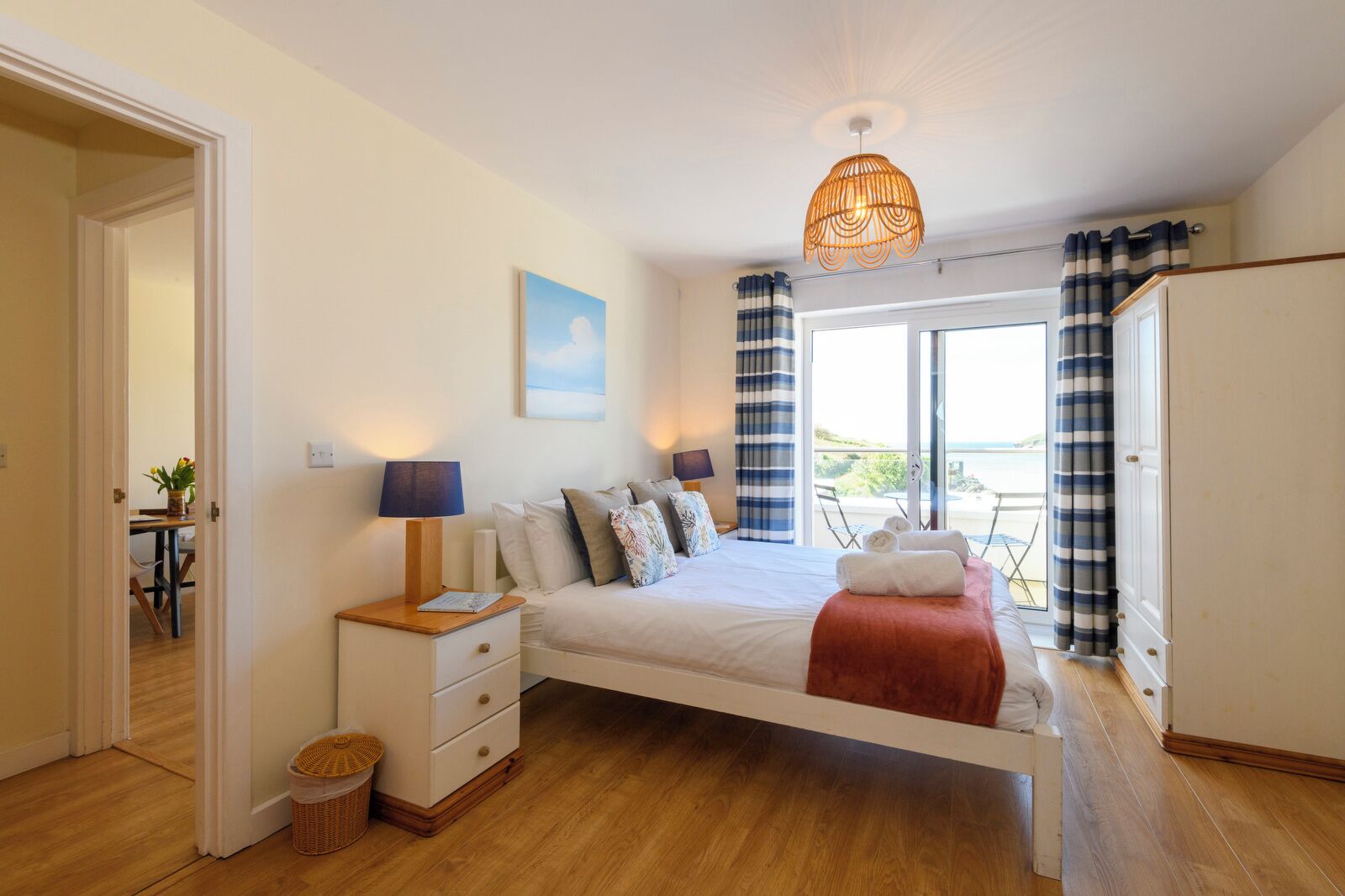 A bedroom with a bed, bedside tables, a window with curtains, and a view of the outdoors.