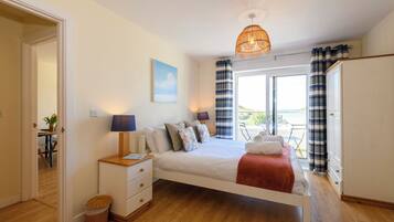 A bedroom with a bed, bedside tables, a window with curtains, and a view of the outdoors.