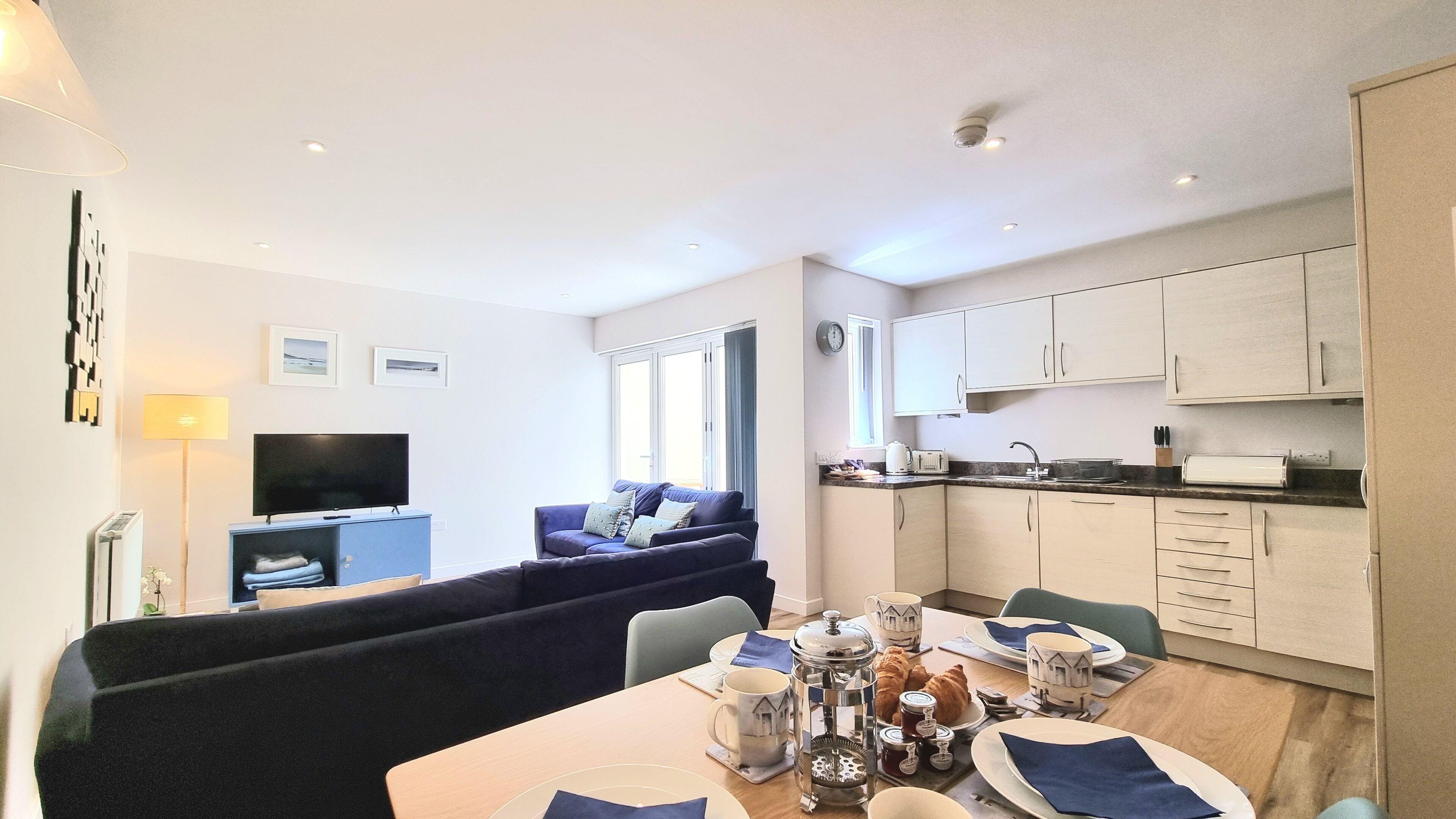 A modern apartment with a living room, dining area, and kitchen.