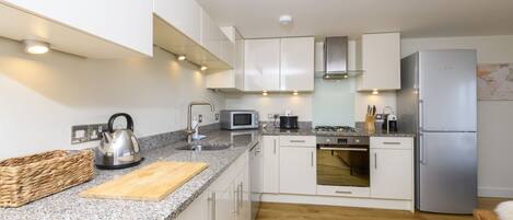A modern kitchen with granite countertops, stainless steel appliances, and wooden flooring.