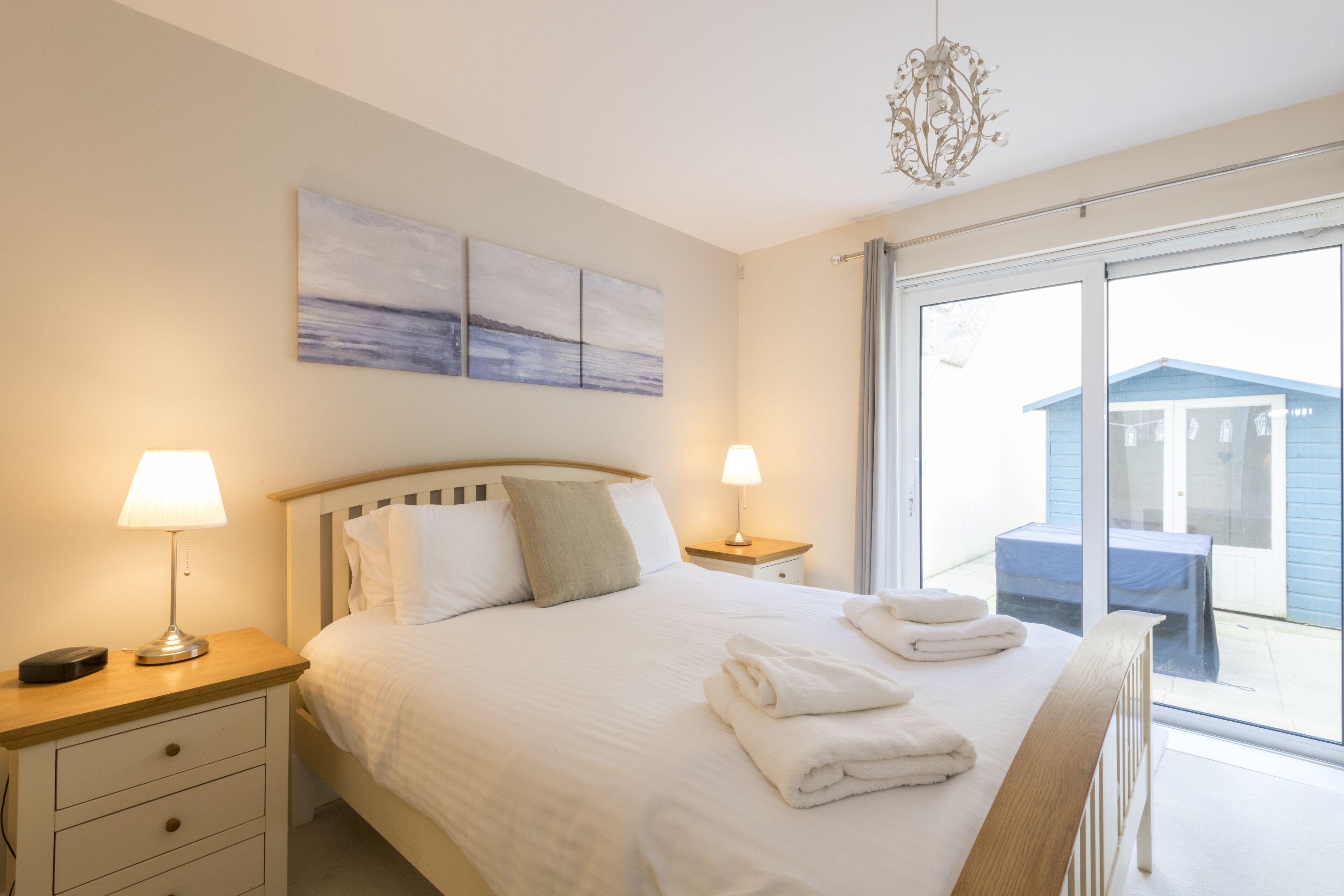 A hotel room with a large bed, two bedside lamps, a view of the outside, and a ceiling light.