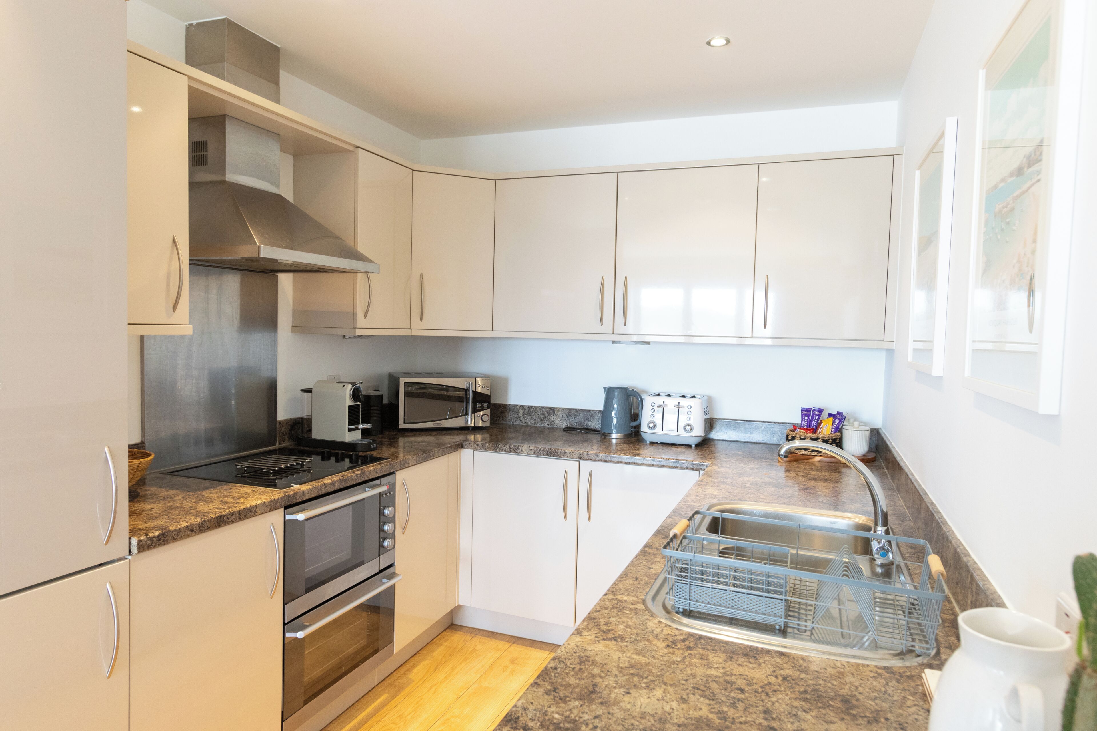 A modern kitchen with stainless steel appliances, white cabinetry, and a granite countertop.