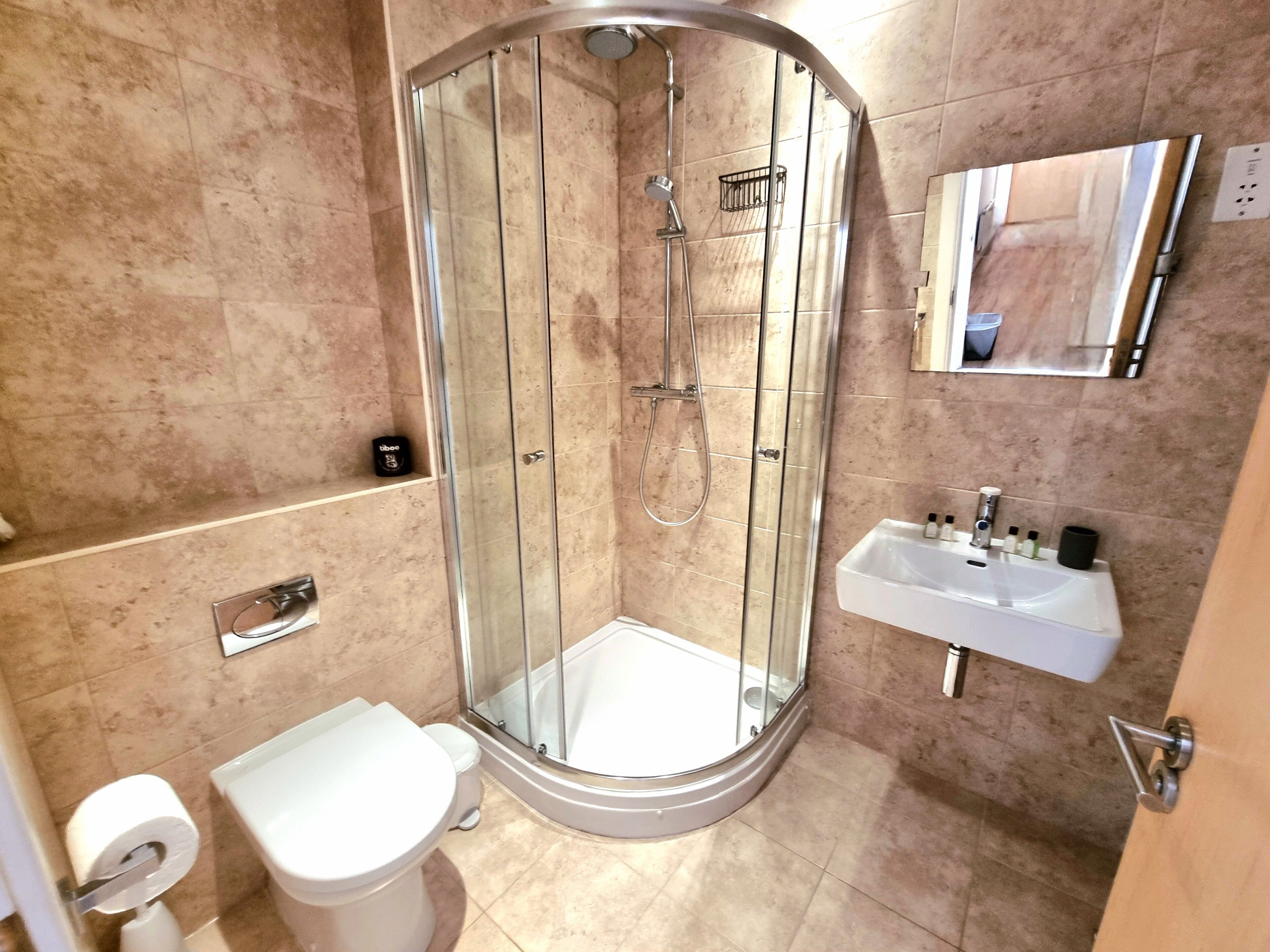 A modern bathroom with a glass-enclosed shower, a white sink, and a toilet.