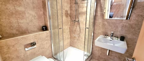 A modern bathroom with a glass-enclosed shower, a white sink, and a toilet.