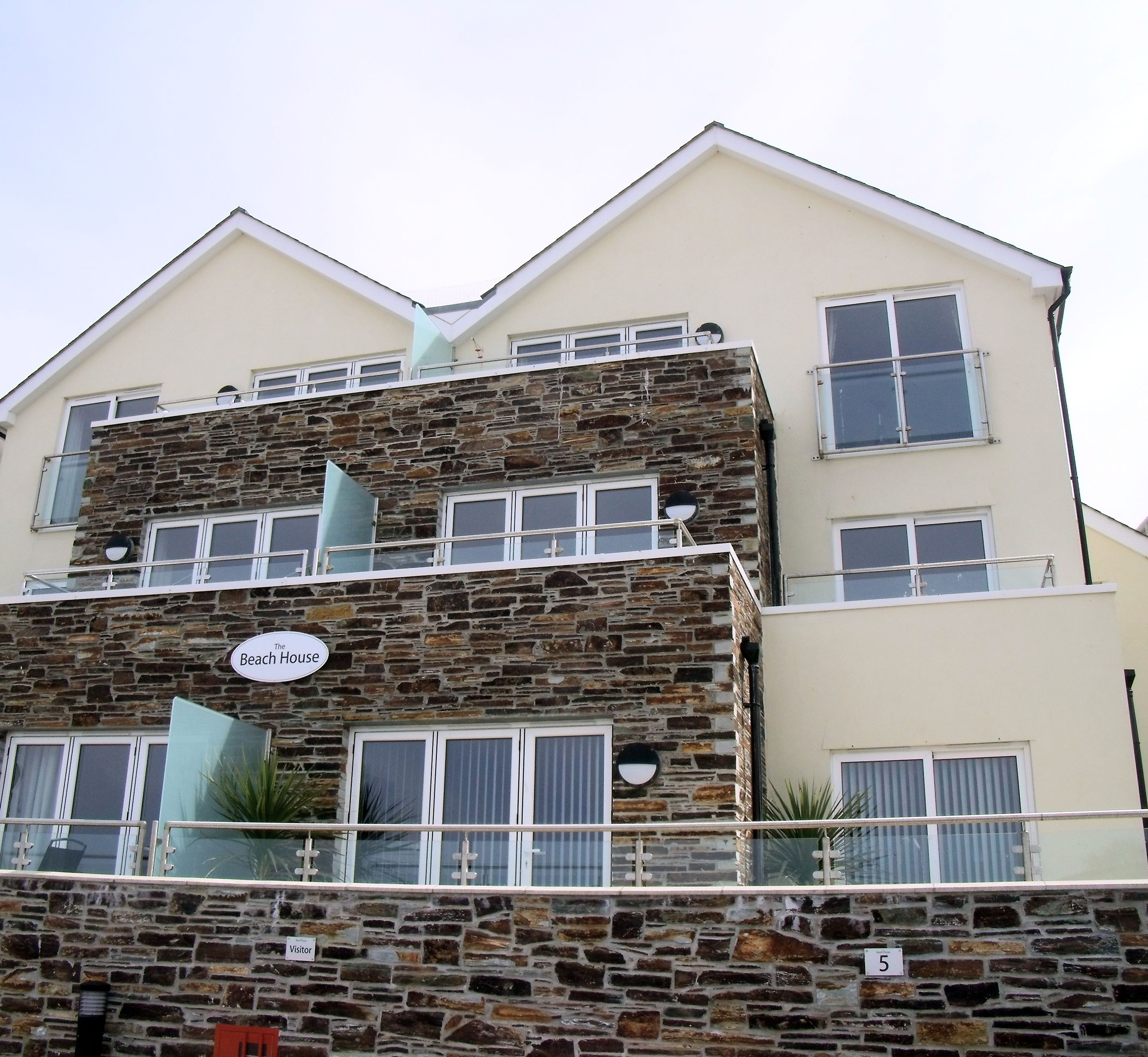 A two-story building with a stone facade and multiple windows. A sign on the building reads "The Beach House."