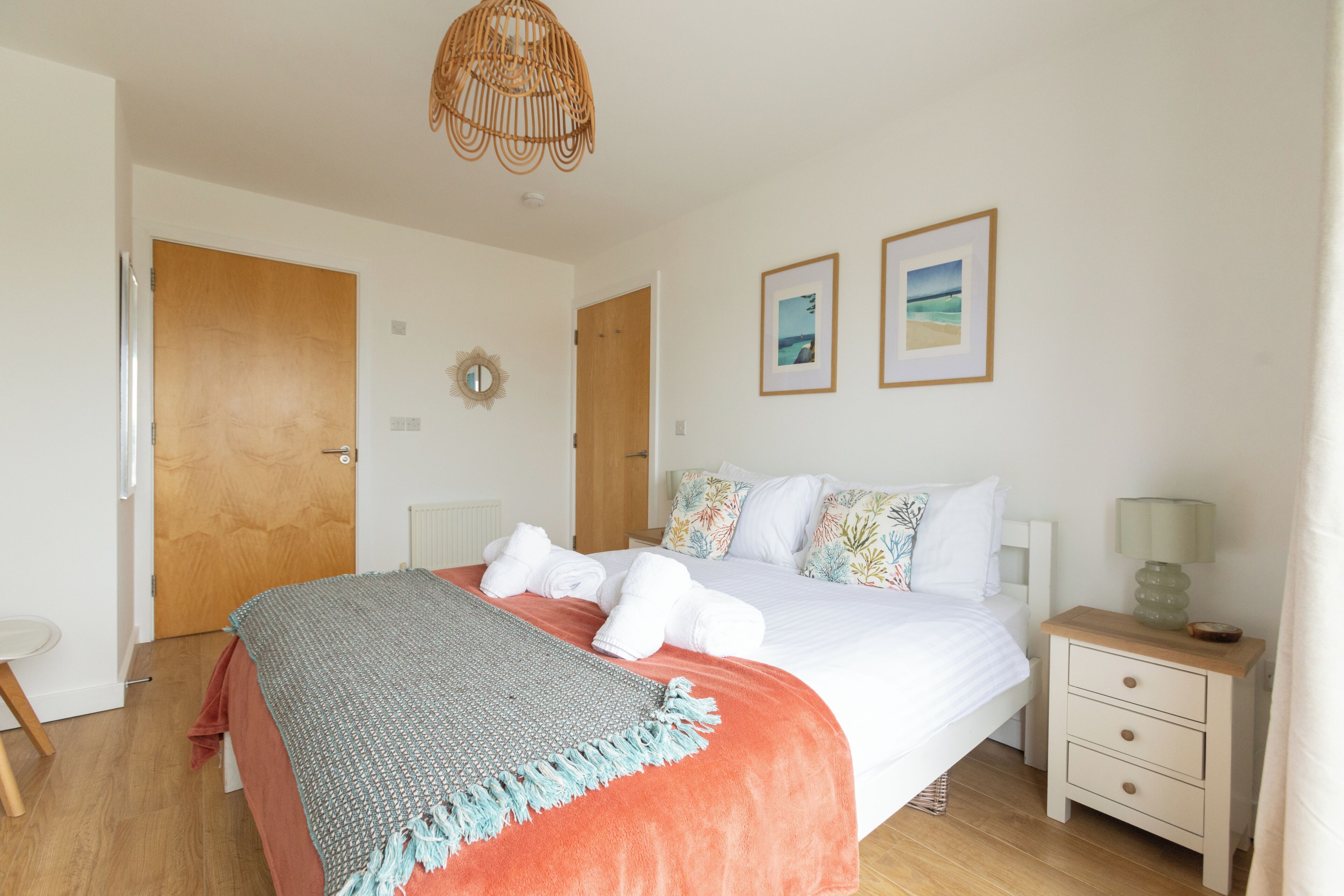 A bedroom with a bed, bedside tables, a lamp, a mirror, and framed pictures on the wall.