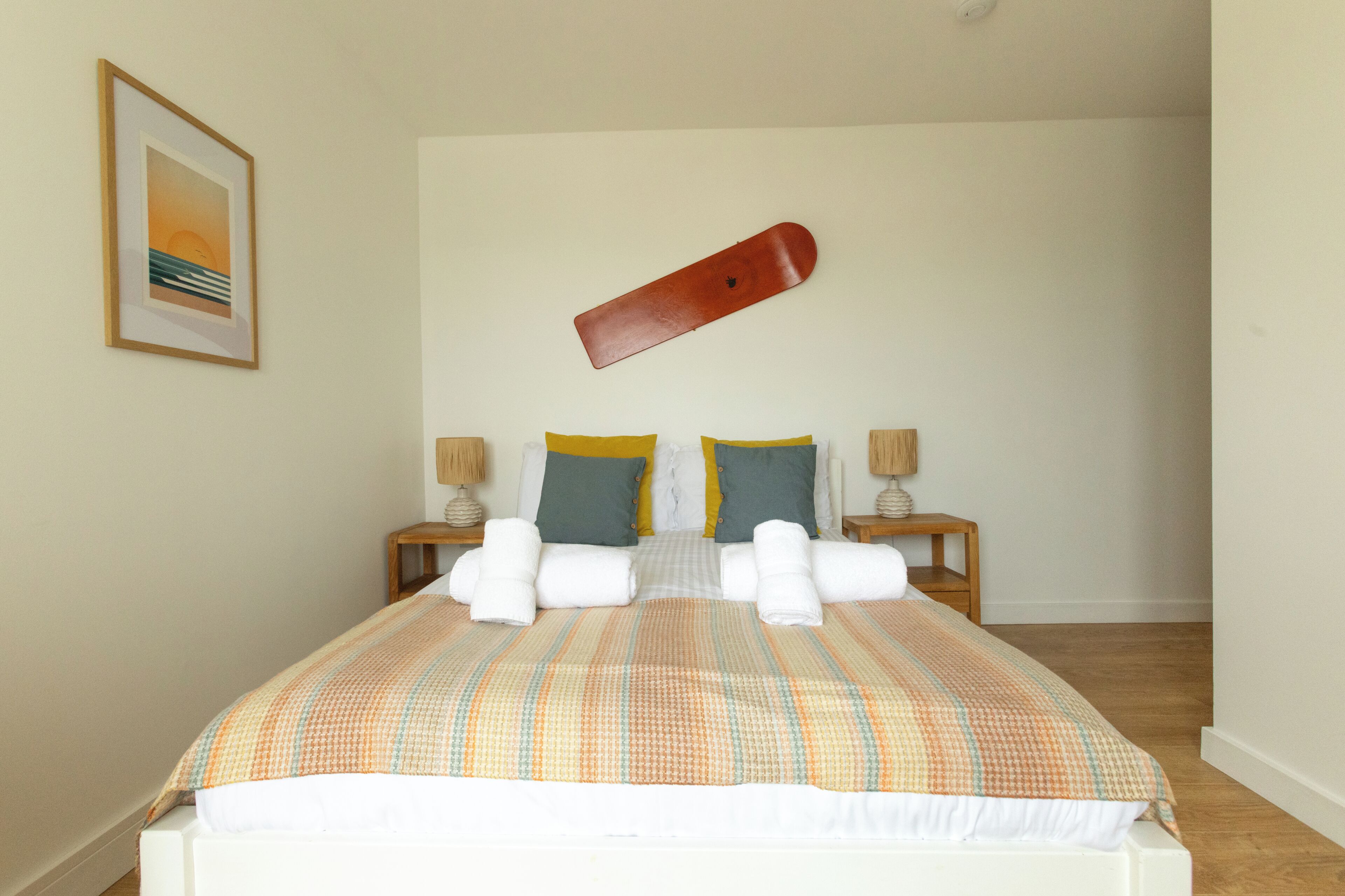 A neatly made bed with a striped bedspread, two pillows, and a pair of towels.