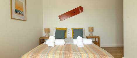 A neatly made bed with a striped bedspread, two pillows, and a pair of towels.
