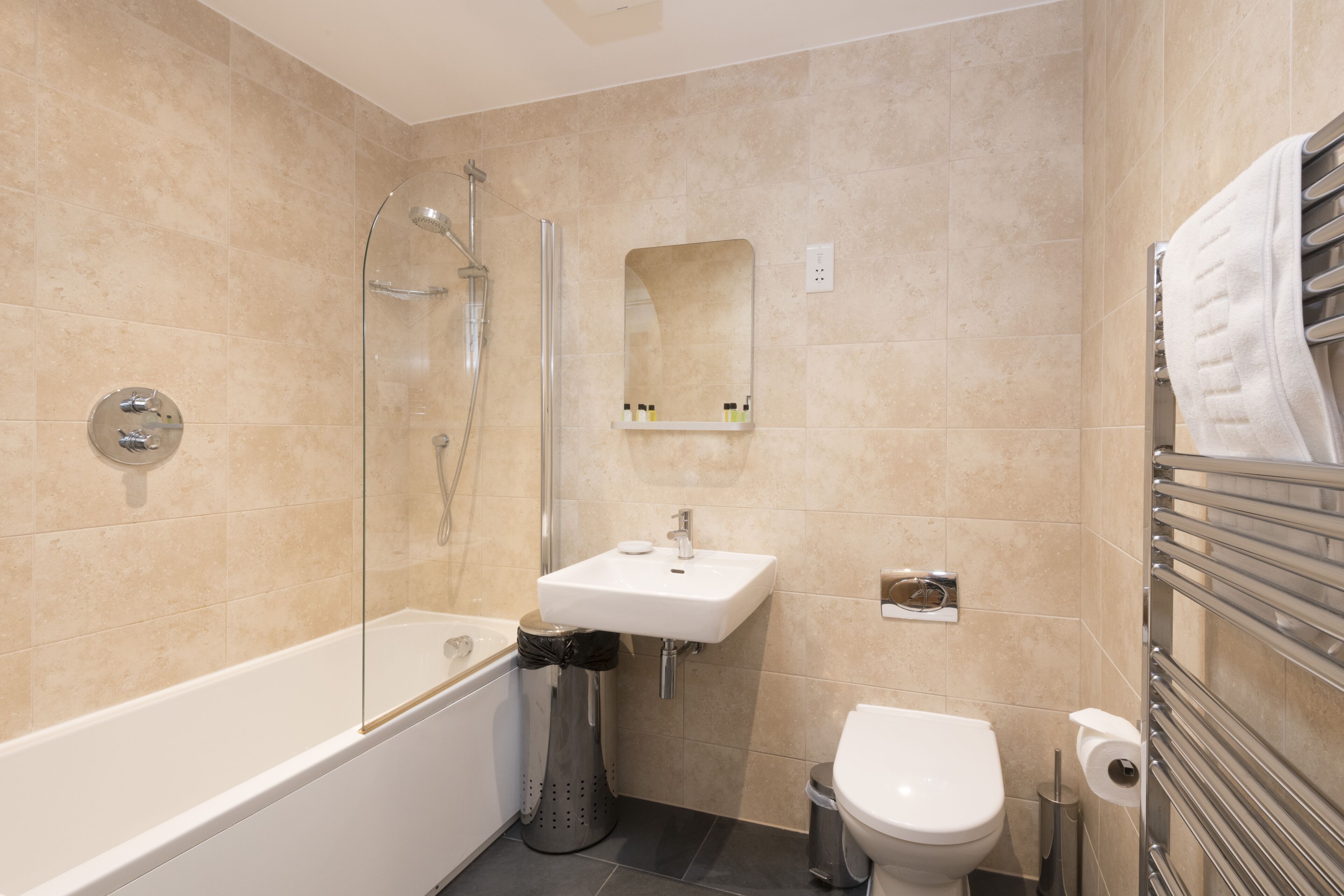 A modern bathroom with a bathtub, a sink, a toilet, and a glass-enclosed shower.