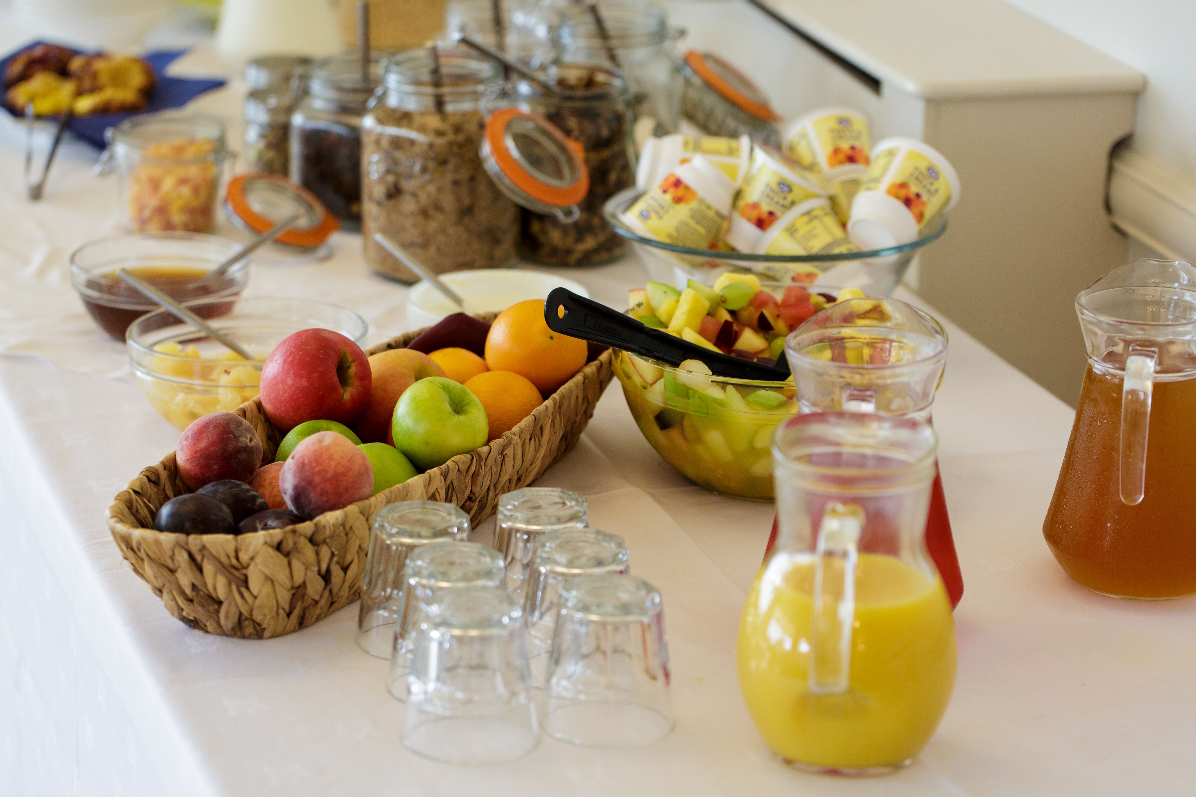 A breakfast buffet with various fruits, condiments, and beverages.