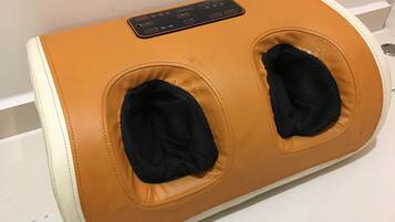 A massage chair with a control panel and two footrests.