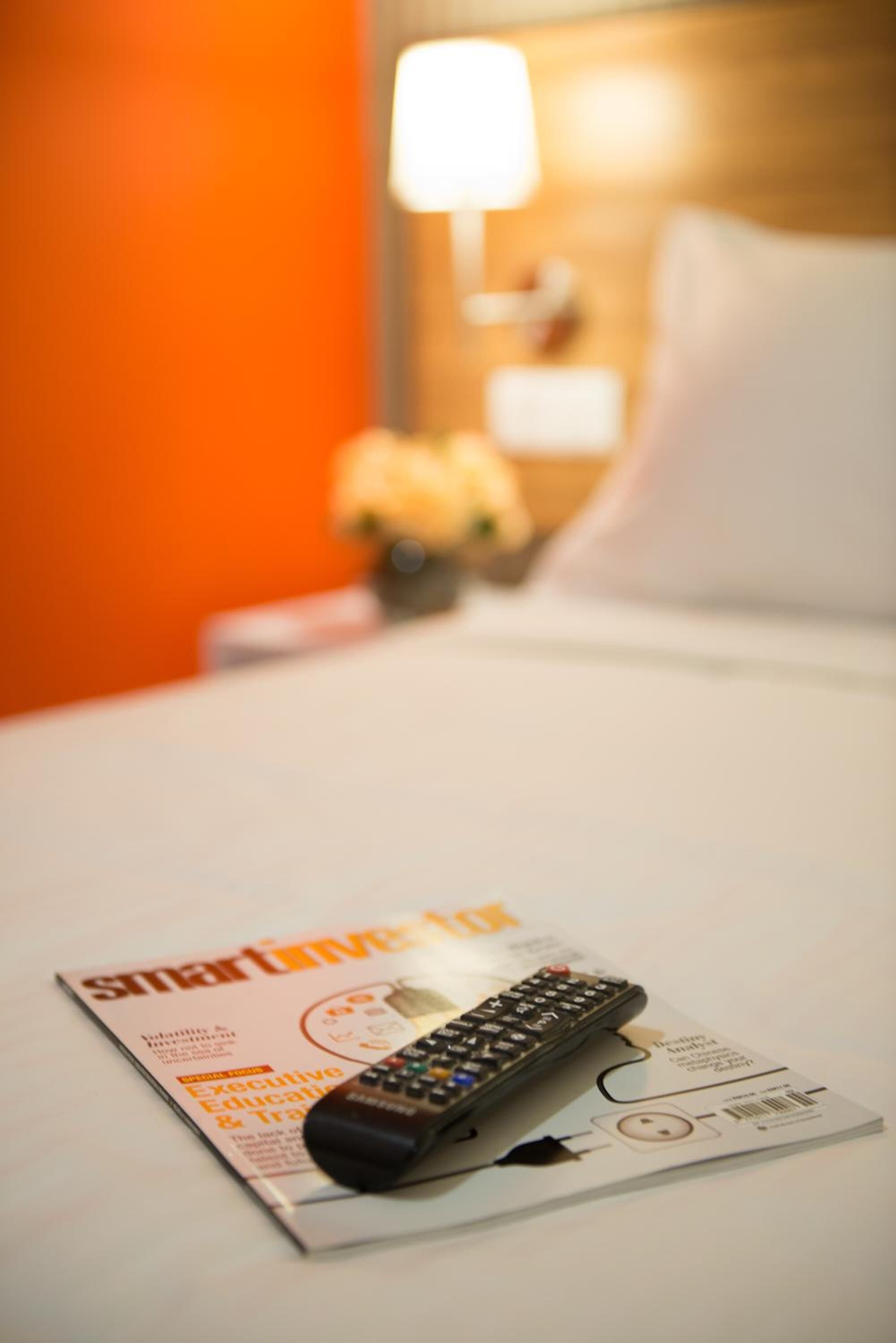 Um comando remoto sobre uma revista, numa cama de um quarto de hotel.