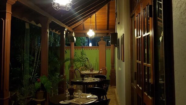 An indoor dining area with wooden ceiling beams, hanging pendant lights, and a table set for dining. - Norfolk Heritage Airport Villa (Seeduwa - Katunayake)