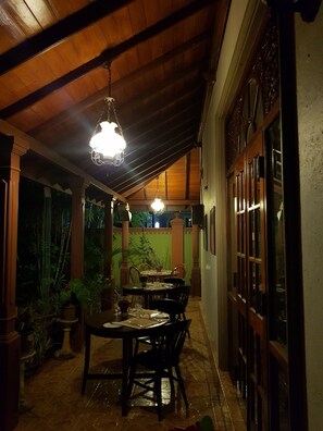 An indoor dining area with wooden ceiling beams, hanging pendant lights, and a table set for dining. - Norfolk Heritage Airport Villa (Seeduwa - Katunayake)