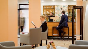 A hotel lobby with a reception desk, seating area, and a bar. - Messehotel Köln-Deutz (Cologne)
