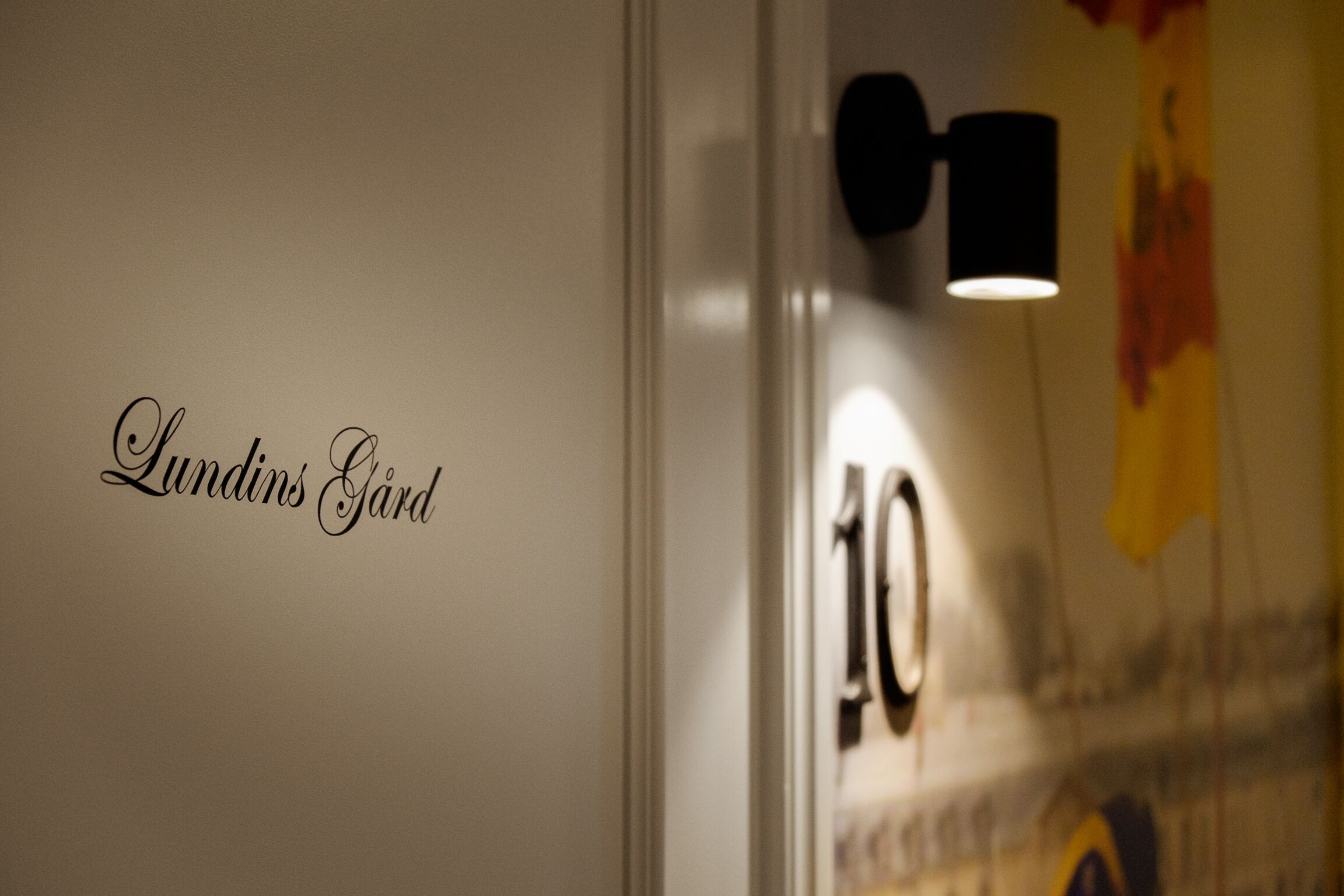 Una pared con el texto "Lundins Gård" y el número "10" parcialmente visible.