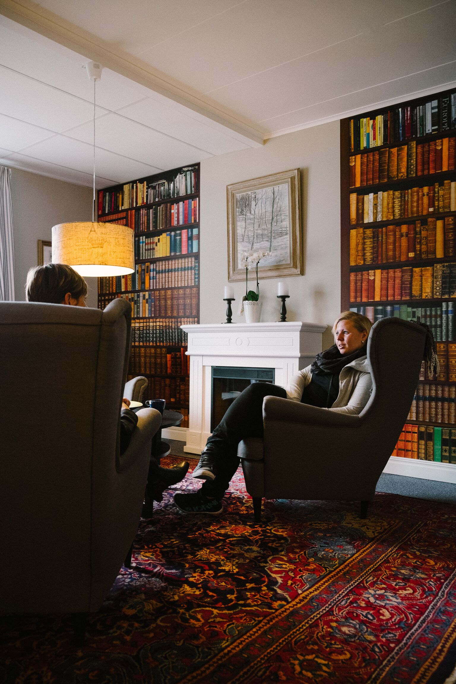 Una biblioteca con estanterías, una chimenea y dos sillones.