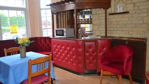 Un restaurant chaleureux avec un bar rouge, des chaises en bois et une nappe bleue.