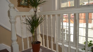 Un escalier avec des balustrades blanches et un pot de fleurs.