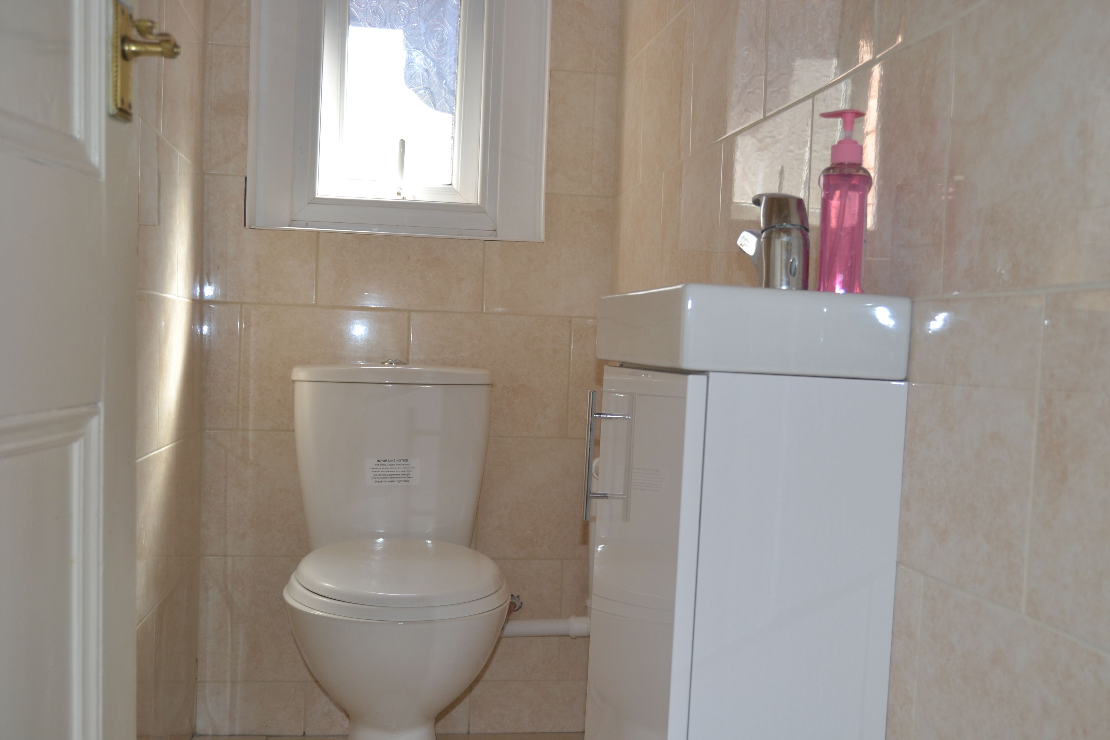 A bathroom with a toilet, a sink, and a window.