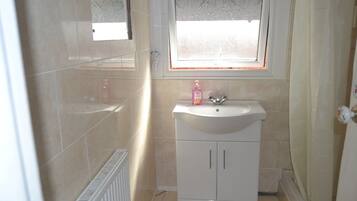 A small bathroom with a white sink, a mirror above it, and a window with a decorative pattern.