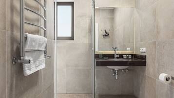 Un baño moderno con cabina de ducha de vidrio, un lavamanos con espejo y un inodoro.