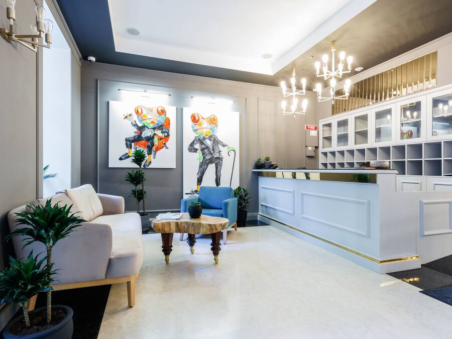 A modern reception area with a light-colored reception desk, a blue armchair, and two potted plants.
